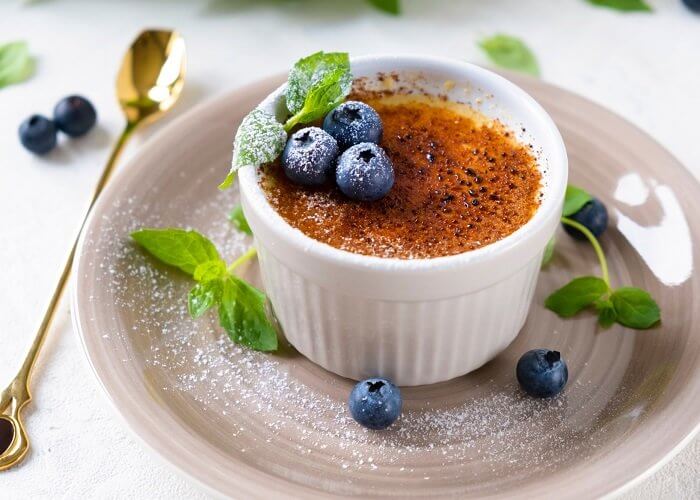 Creme brulee dessert with blueberries and mint leaves. Close up.