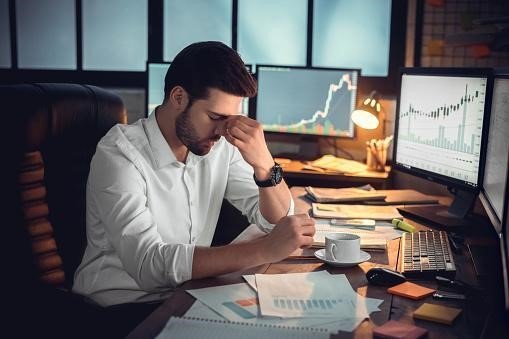 A frustrated trader sitting in front of his trading screens