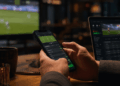 Hands placing online football bets on a smartphone